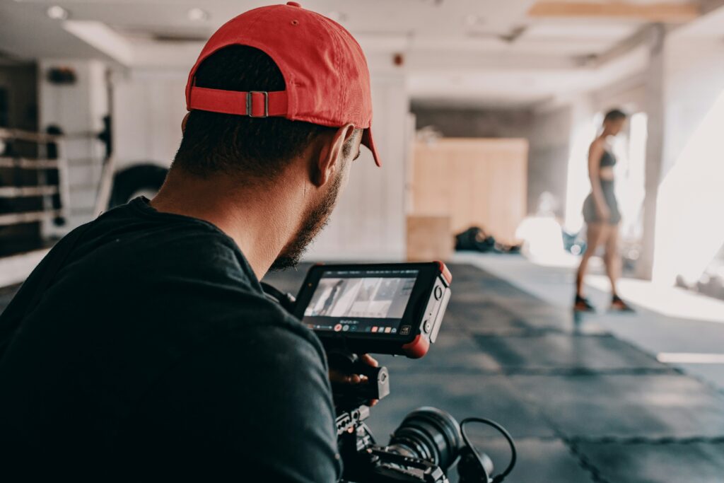 A videographer films a fitness session using professional equipment to capture dynamic angles and ensure high-quality footage for the active environment.