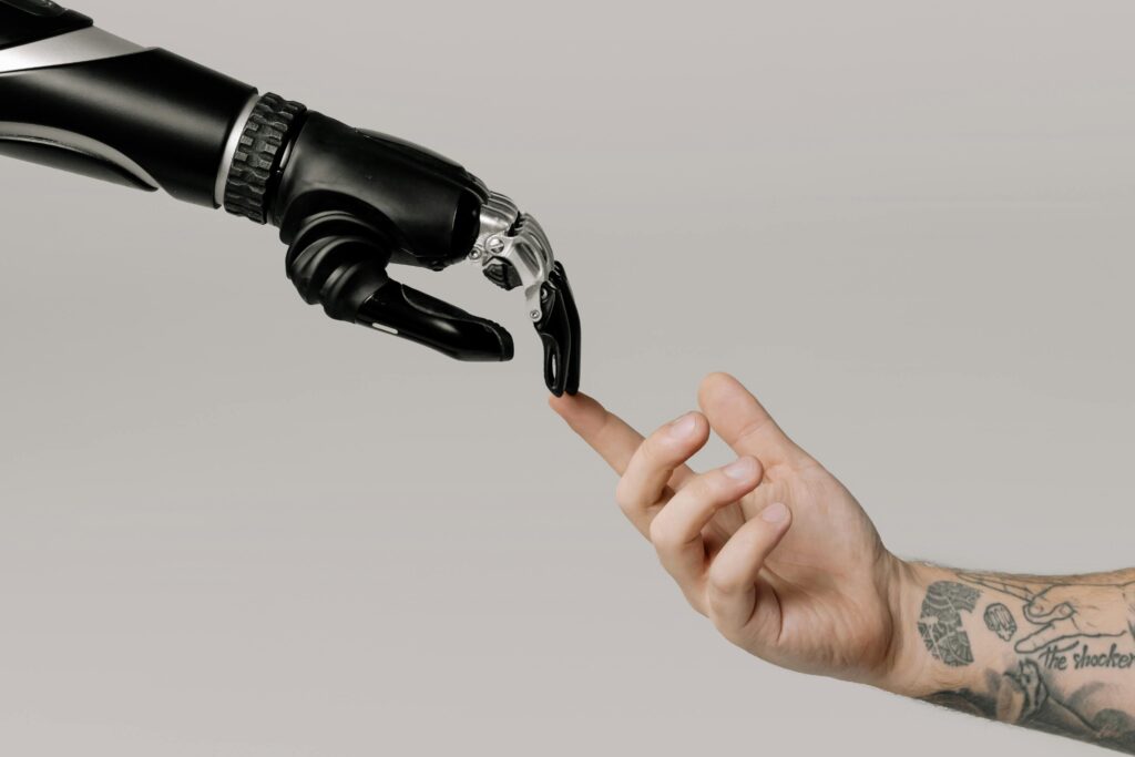 Bionic Hand and Human Hand Finger Pointing. Photo by cottonbro studio: https://www.pexels.com/photo/bionic-hand-and-human-hand-finger-pointing-6153354/