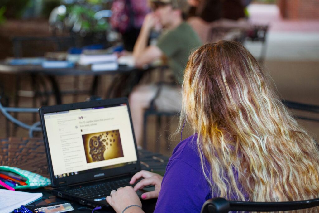Women in purple shirt sitting and researching on a laptop