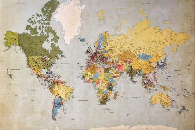 Blue, green and yellow world map with pins on them.